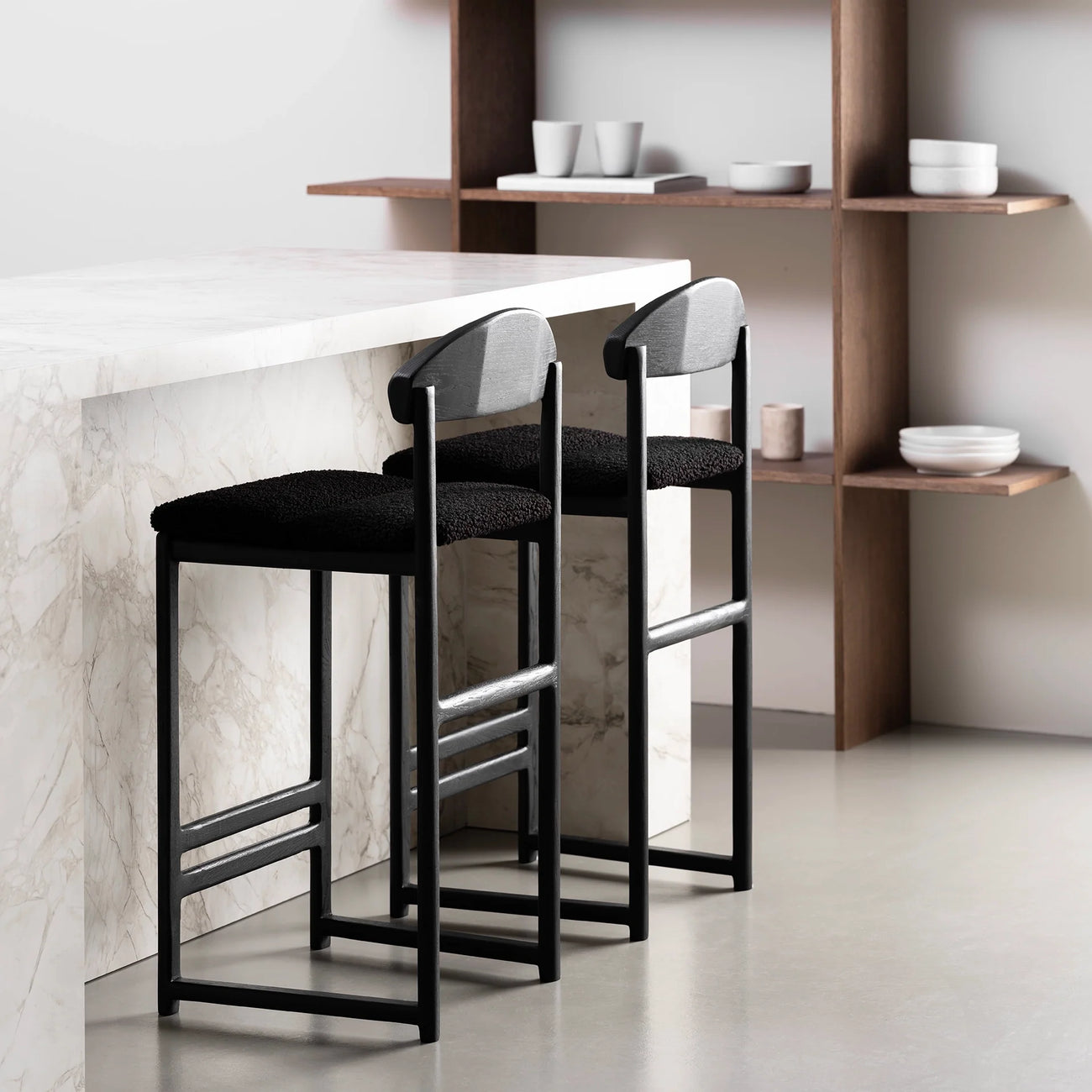 Sleek black oak bar stools with black bouclé seats at a modern kitchen counter.