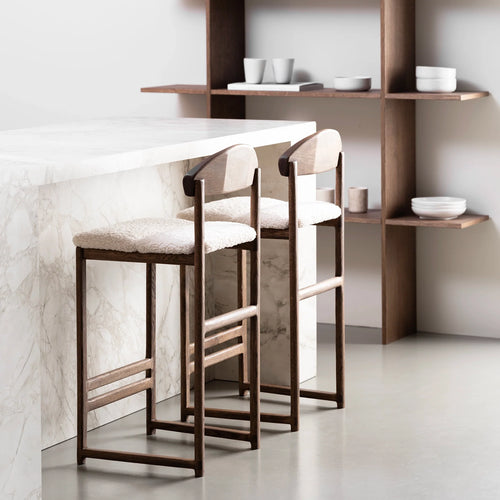 Dark oak bar stools with ivory bouclé seats, perfect for enhancing kitchens and bar areas with contrast and comfort.