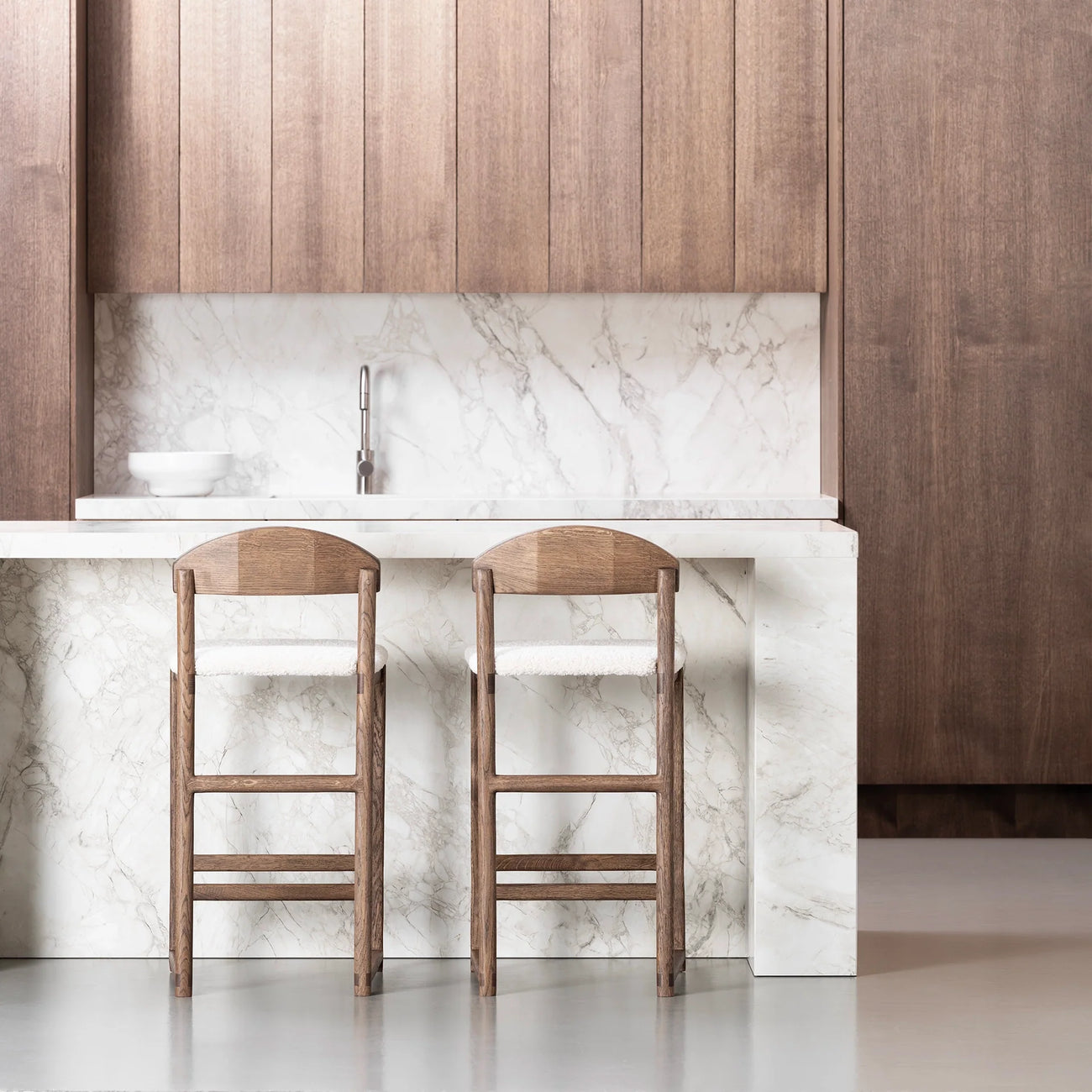 Elegant kitchen with two wooden bar stools and a marble countertop, showcasing modern design and style.