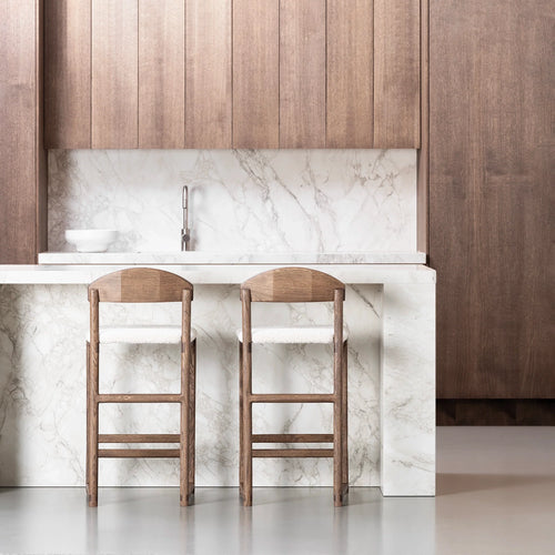Elegant kitchen with two wooden bar stools and a marble countertop, showcasing modern design and style.