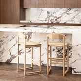 Oak Bar Stool Ted in a modern kitchen with a marble countertop and wooden cabinetry.