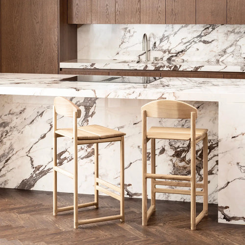 Ted bar stool in solid oak, minimalistic design, stylishly placed at a modern kitchen island with marble countertop.