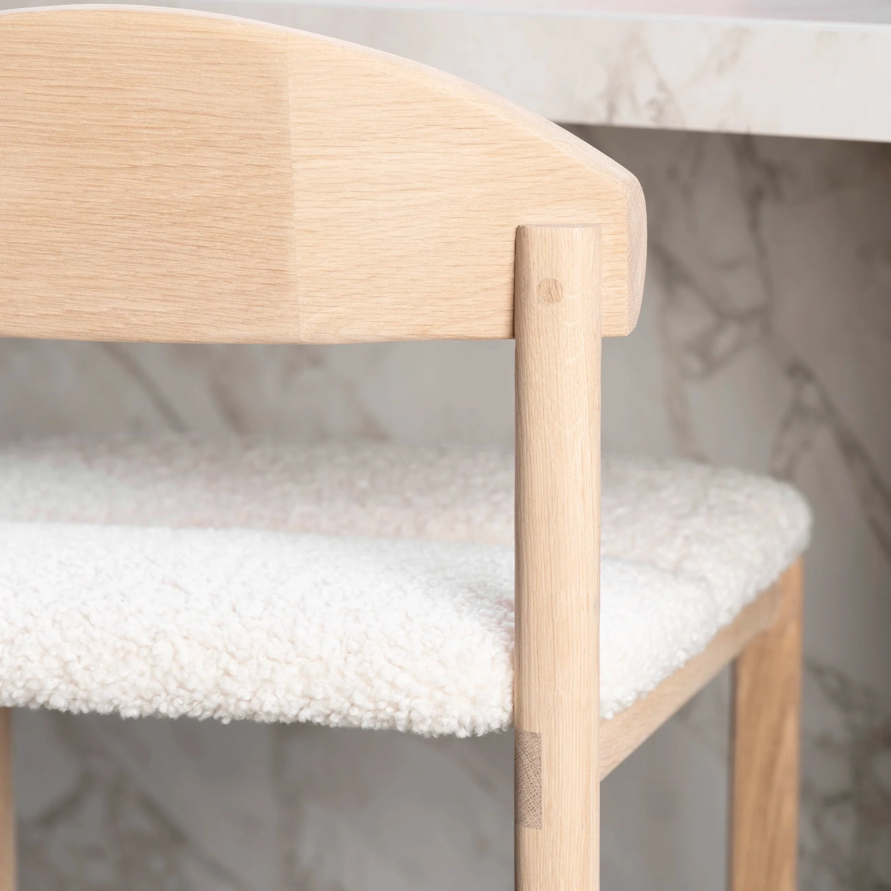 Oak bar stool with ivory bouclé seat, showcasing modern design and warm tones for stylish seating.