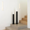 Scandinavian black floor candleholders with glass cylinders on a staircase