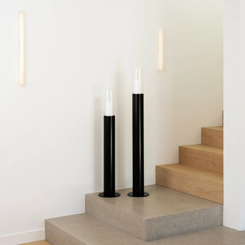 Scandinavian black floor candleholders with glass cylinders on a staircase