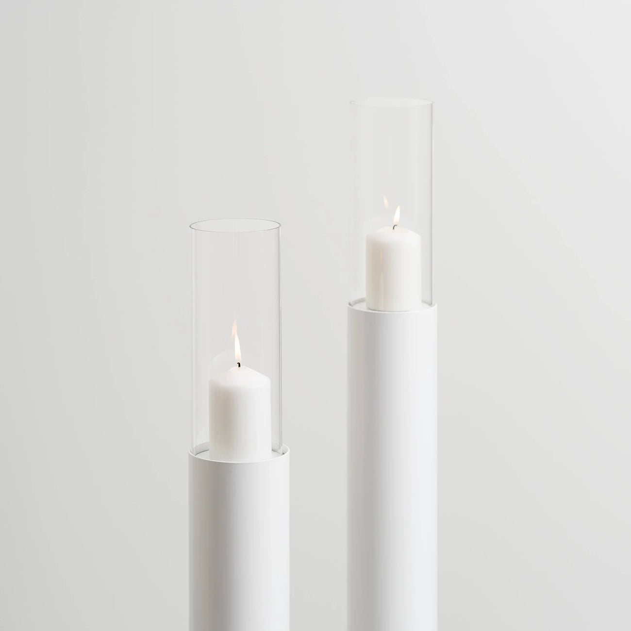 Set of 2 white floor candleholders with minimalist design, featuring candles in elegant glass holders.