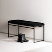 Wilma bench in black bouclé with clean lines, ideal for a minimalist décor, paired with stylish black boots.