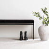 Wilma black bouclé bench with clean lines, minimalist design, and stylish black boots beside a textured vase.