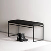 Wilma bench in black with vegan leather seat, minimalist design for modern spaces, paired with black boots.