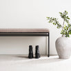 Wilma bench in black with greige bouclé, styled with black boots and a decorative vase for modern interiors.