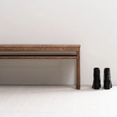 Oak Bench in dark oak frame beside black boots on a neutral background, perfect for hallways or entryways.