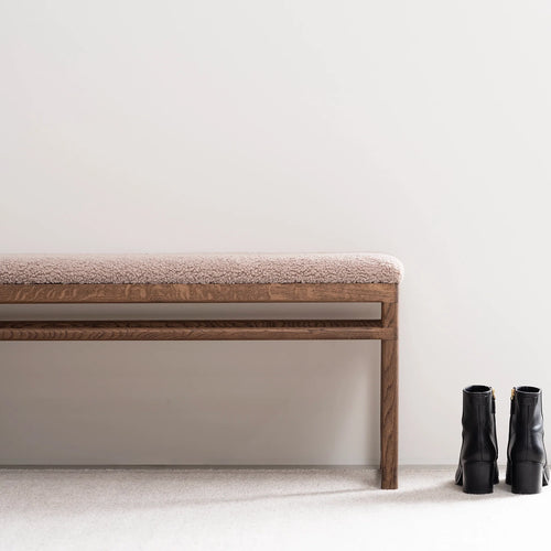 Wilma wood bench in dark oak with greige bouclé upholstery, perfect for modern interiors, paired with stylish black boots.
