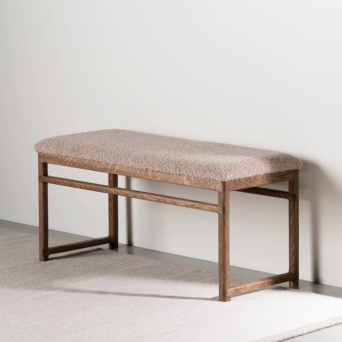 Wilma wood bench in dark oak with greige bouclé upholstery, ideal for modern interior spaces.
