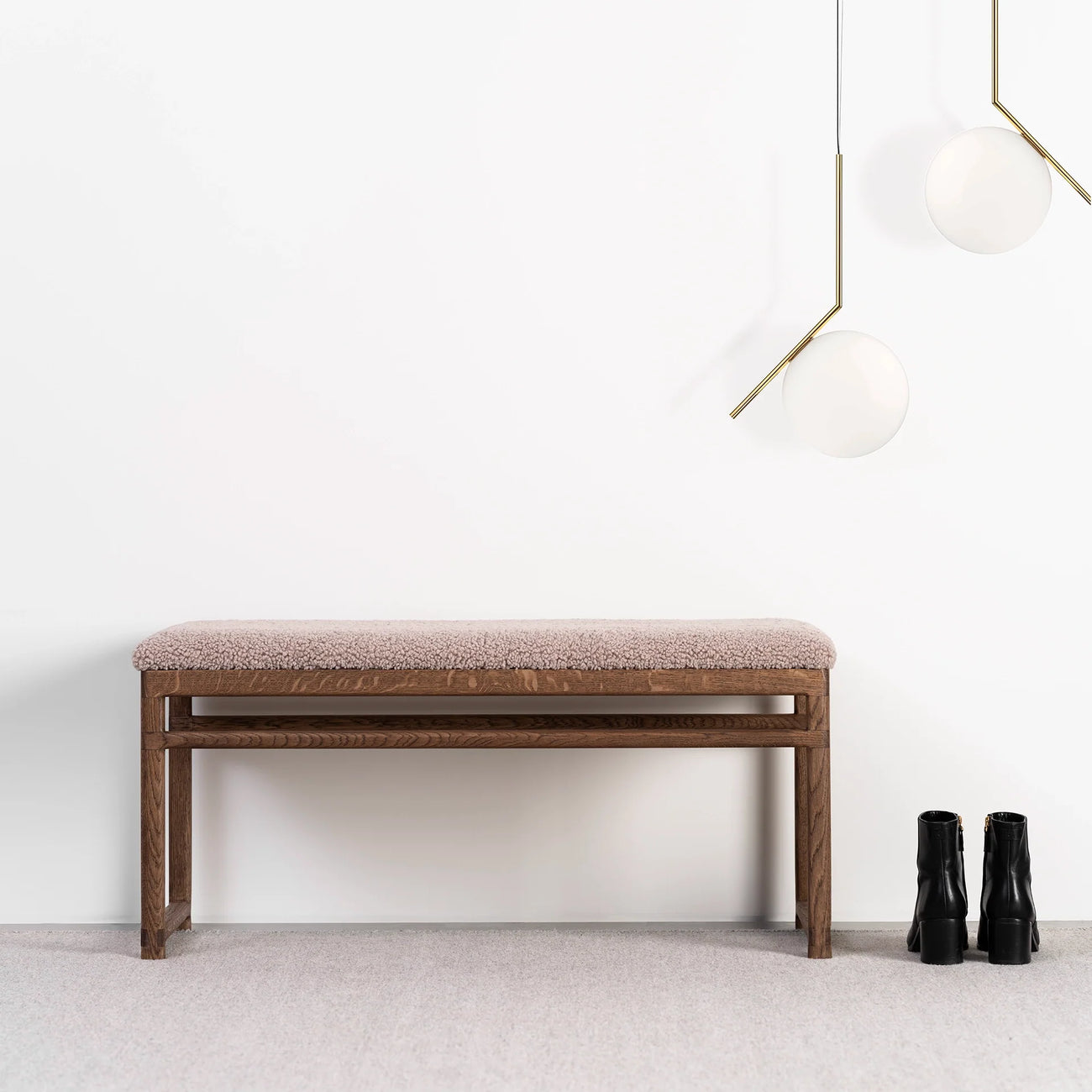Wilma wood bench in dark oak with greige bouclé, ideal for modern interiors, styled with black boots and elegant lighting.