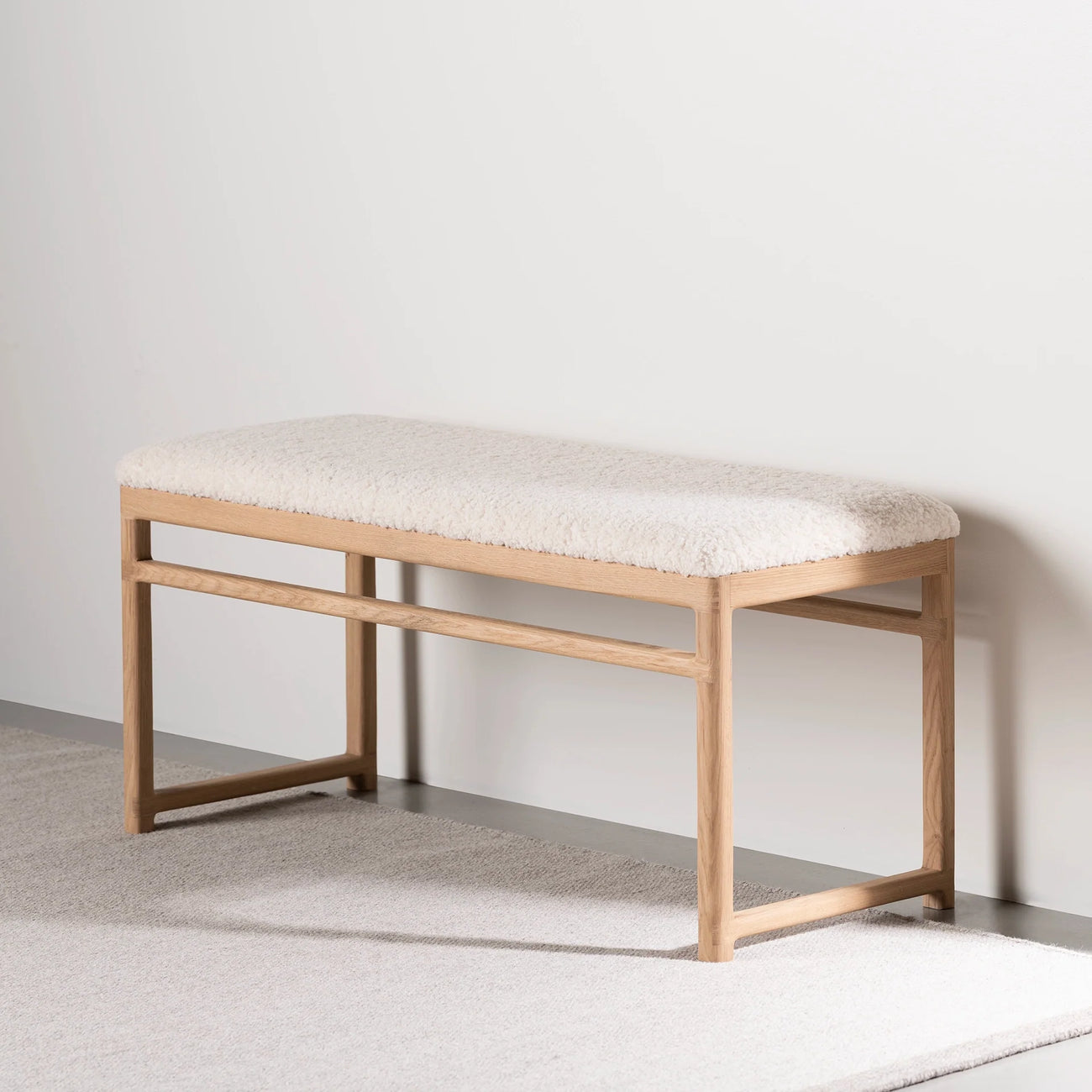 Wilma wood bench in natural oak with ivory bouclé upholstery, perfect for any room decor.